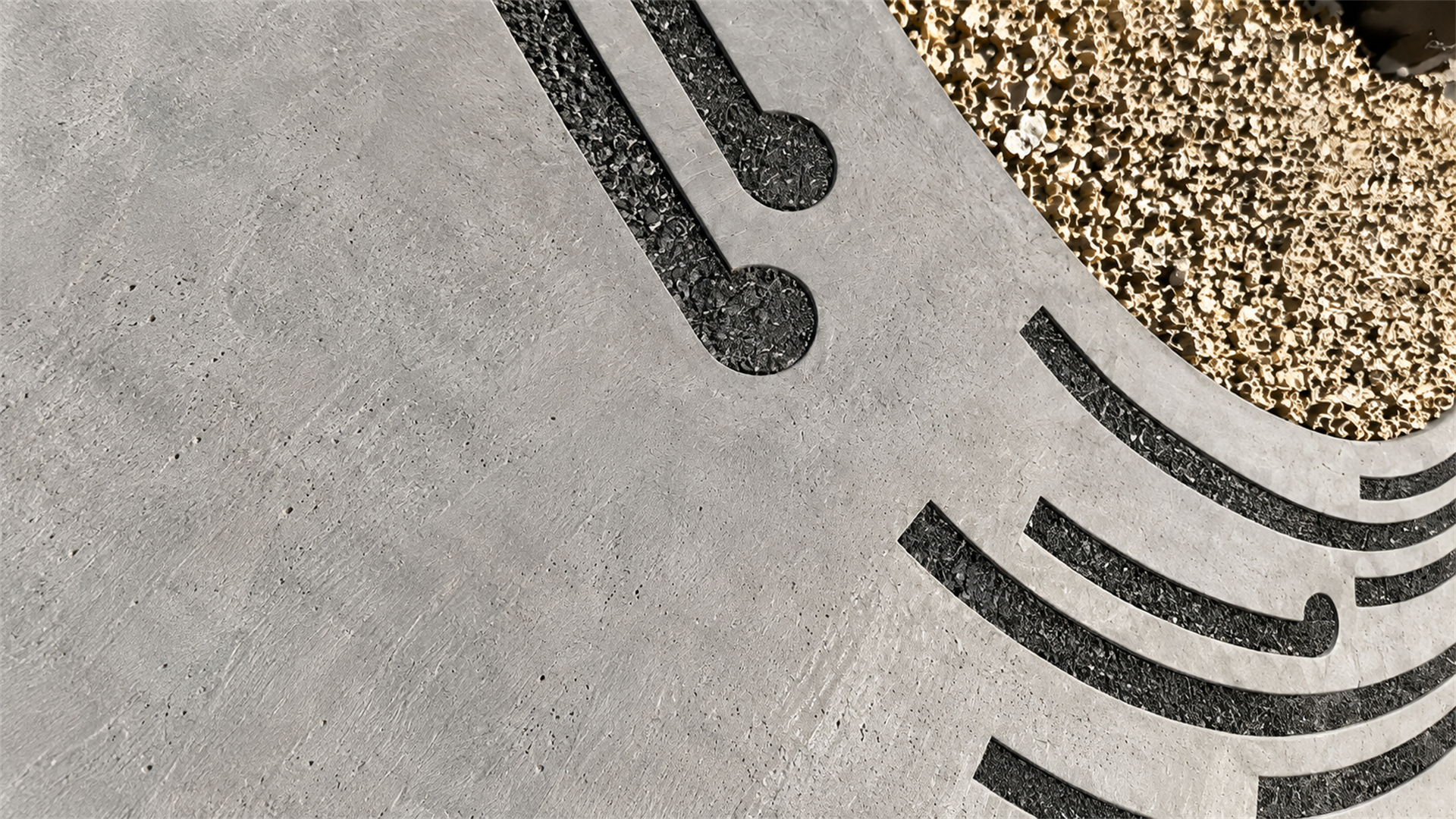 Close surface study of carved charcoal stone, pale aggregate meeting dark inlaid curving lines