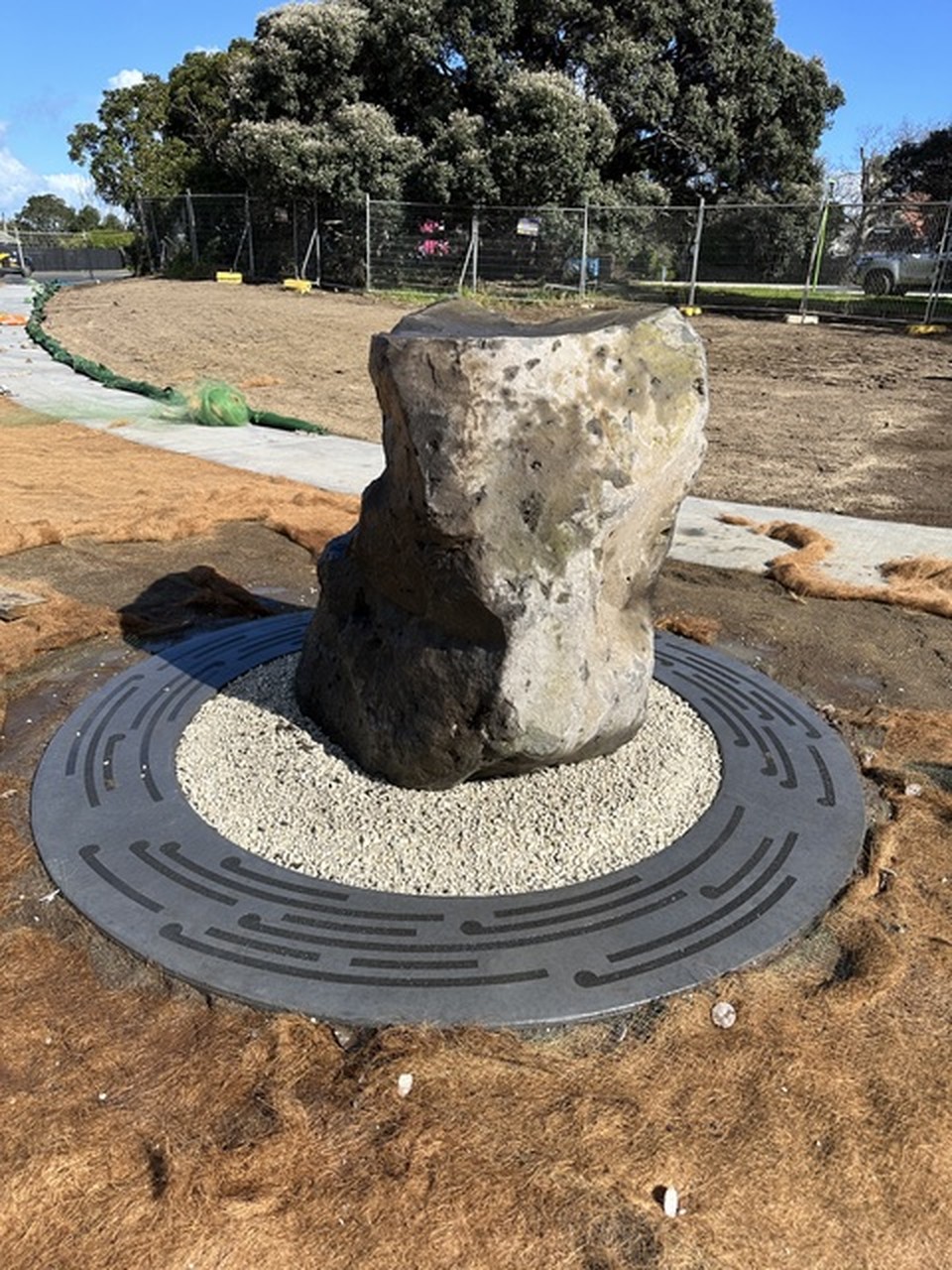 Upright rough-hewn stone standing on a circular gravel base