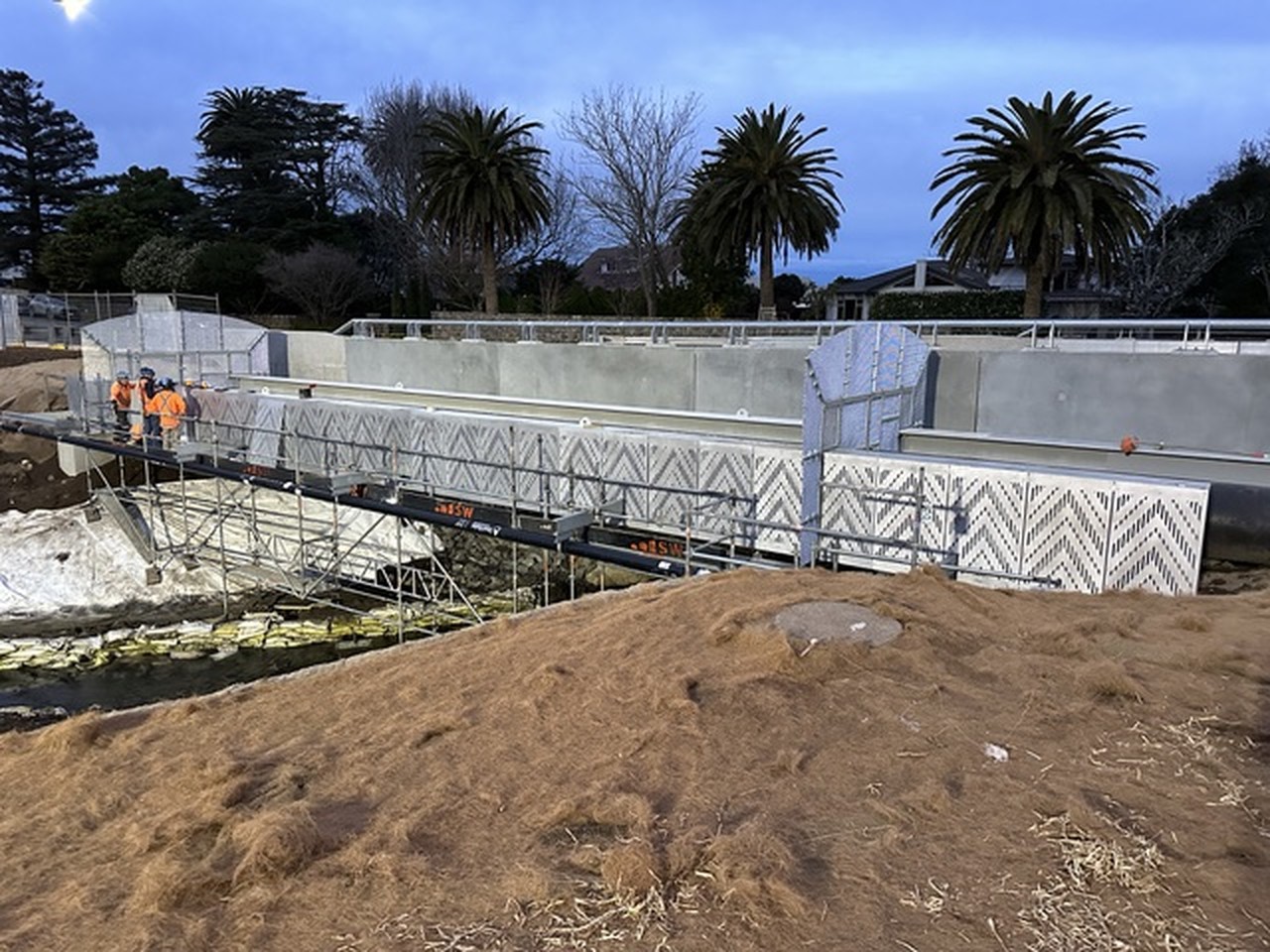 Long perforated concrete artwork sited along a public path