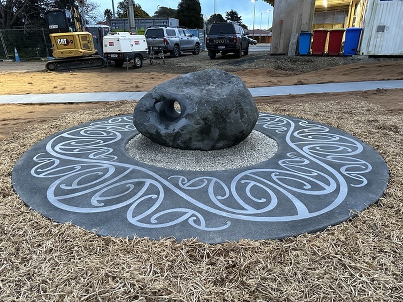 Rounded charcoal stone resting on a large swirl-patterned circular ground inlay