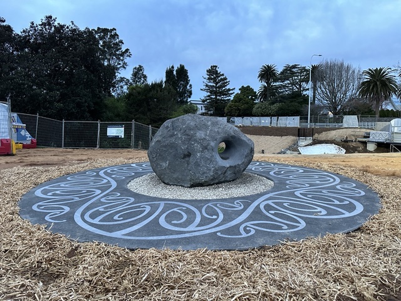 The rounded stone sculpture on its patterned circular base under open sky