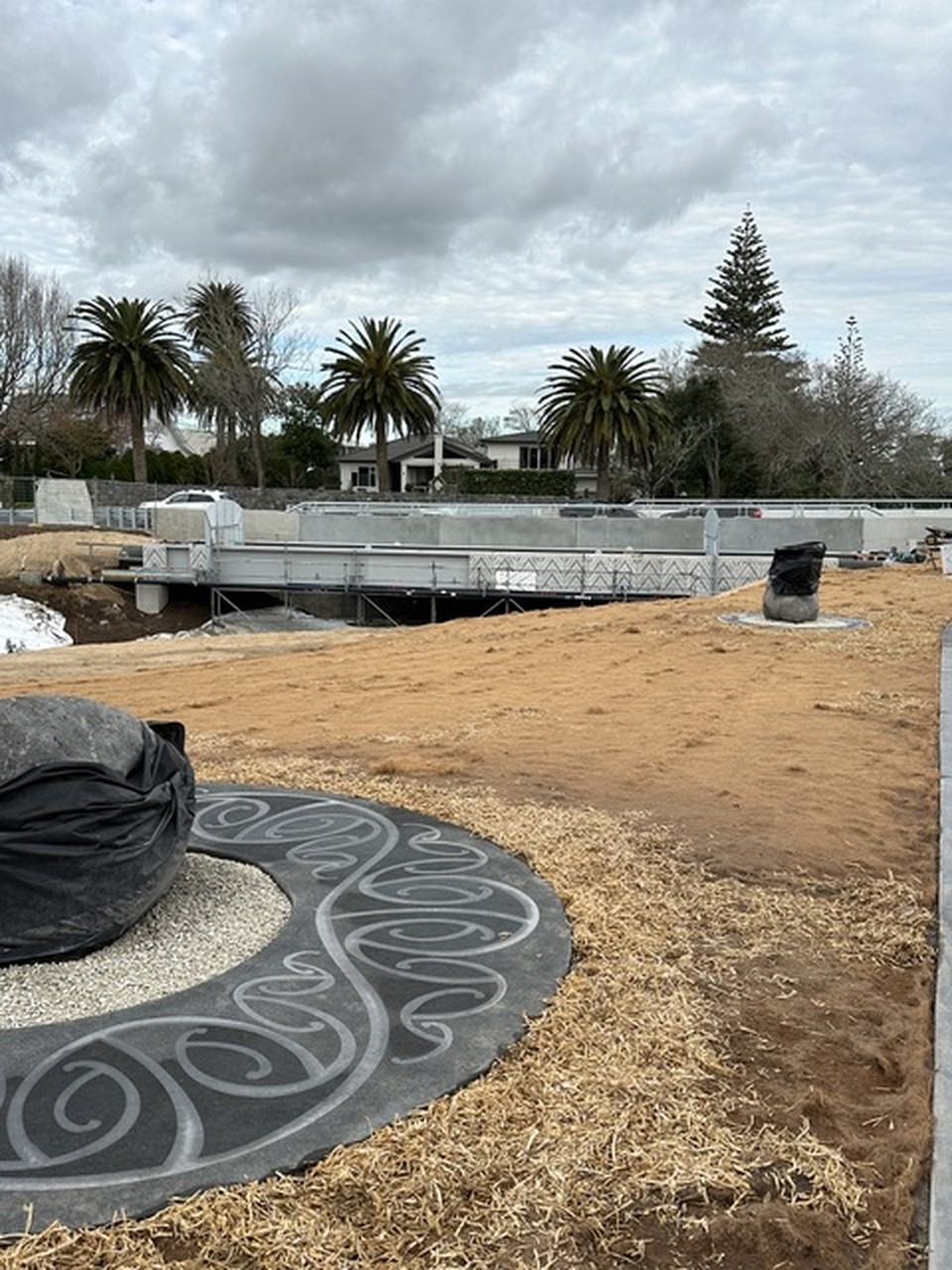 Circular ground inlay and sculpture, wide public-site view